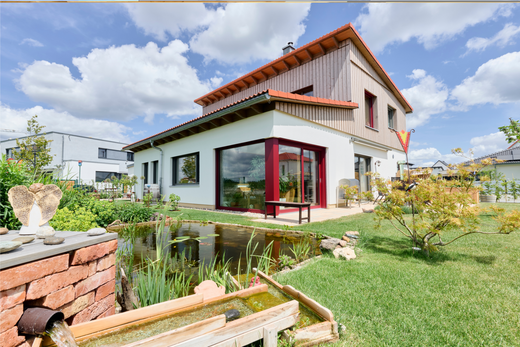 Naturnah-Haus von Aischtaler Holzhaus mit liebevoll gestaltetem Garten samt Teich, Pflanzen und Wasserlauf.