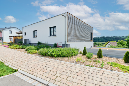 Kubikhaus von Aischtaler Holzhaus mit bepflanztem Vorgarten, Natursteinweg und vertäfelter Fassade.