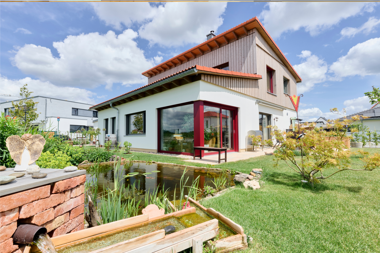 Naturnah-Haus von Aischtaler Holzhaus mit liebevoll gestaltetem Garten samt Teich, Pflanzen und Wasserlauf.