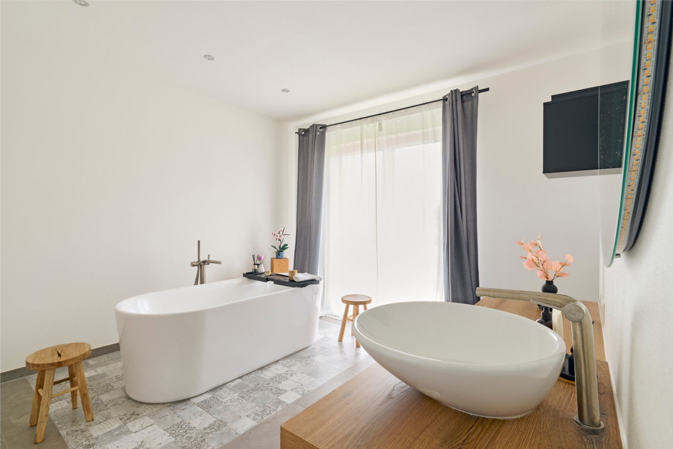 Badezimmer im Kubikhaus von Aischtaler Holzhaus mit freistehender Badewanne, Aufsatzwaschbecken und Tageslicht.