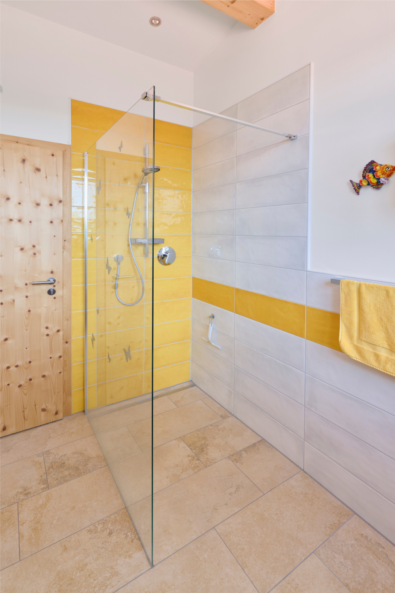Modernes Badezimmer im Naturnah-Haus von Aischtaler Holzhaus mit gelb-weißen Fliesen und bodengleicher Dusche mit Glaswand.