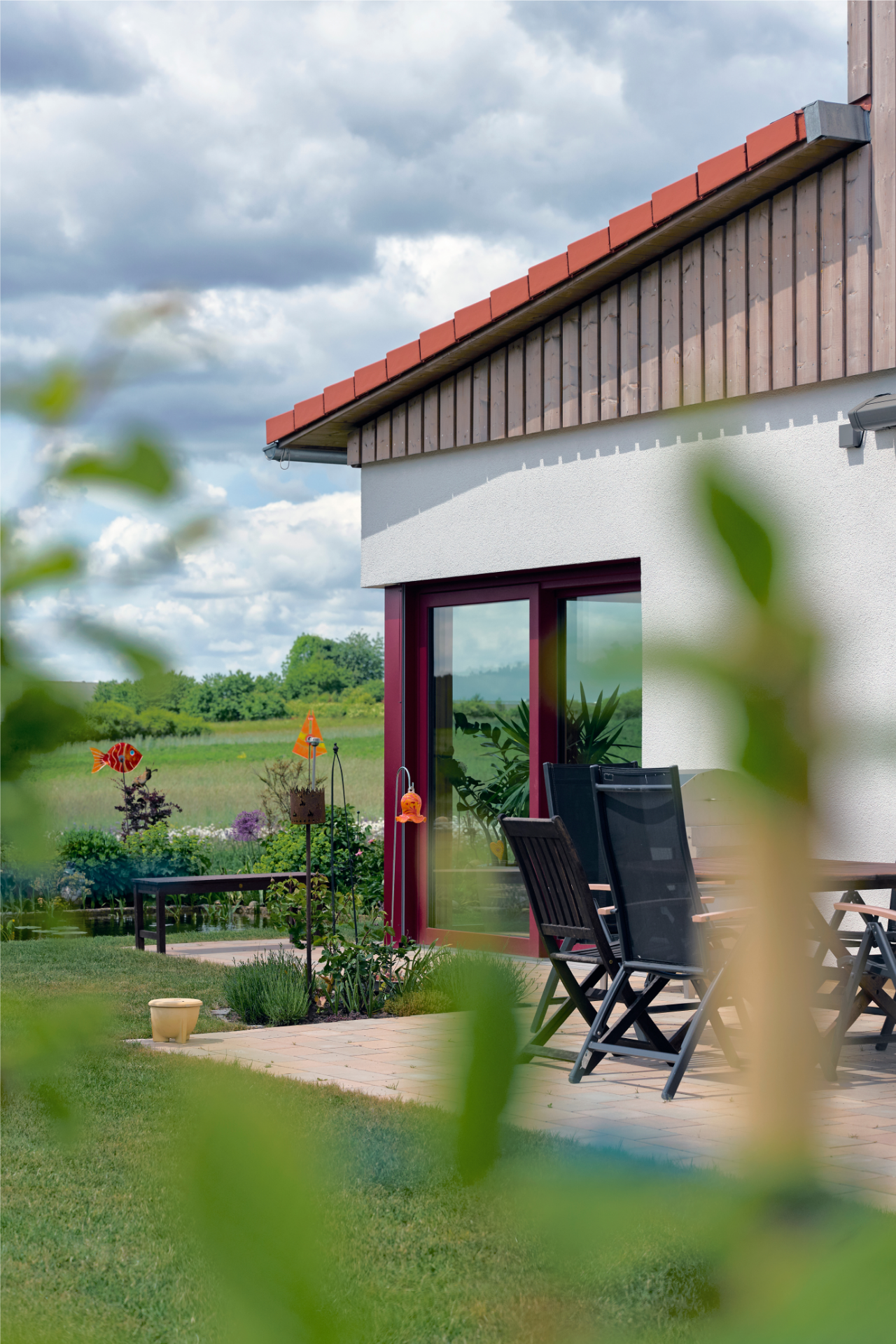 Terrasse des Naturnah-Hauses von Aischtaler Holzhaus mit Gartenmöbeln und freiem Blick auf die angrenzenden Felder und Wiesen.