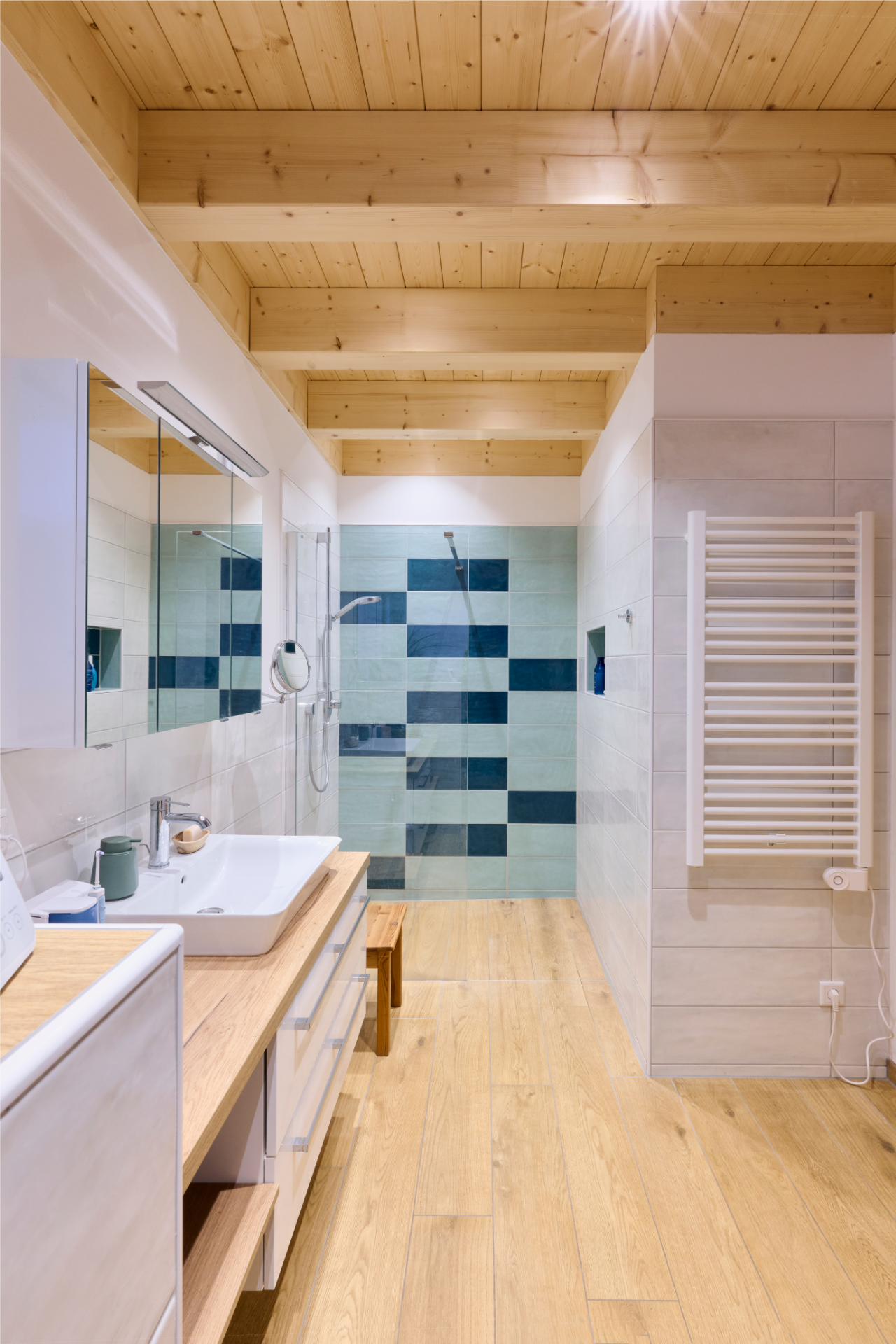 Badezimmer im Naturnah-Haus von Aischtaler Holzhaus mit Holzboden, großer Dusche und blauen Wandfliesen.