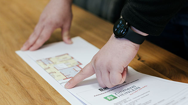 Gefalteter Bauplan als Symbol für individuelle Zusatzleistungen bei Aischtaler Holzhaus